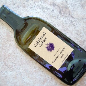 May include: A dark green glass bottle shaped like a wine bottle with a label that reads "Cakebread Cellars Napa Valley Cabernet Sauvignon 2006".