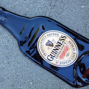 May include: A black glass bottle with a gold label that reads "Guinness, Traditionally Brewed, Extra Stout, St. James's Gate Dublin".