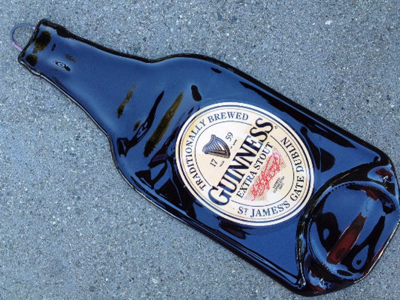 May include: A black glass bottle with a gold label that reads "Guinness, Traditionally Brewed, Extra Stout, St. James's Gate Dublin".
