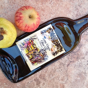 May include: A brown glass bottle with a label that says "Extra Virgin Olive Oil, Italian Selection, Barozzi Emilio". The bottle is lying on a tiled surface with two apples and a pear beside it.