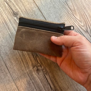 May include: A small brown canvas zipper pouch with a black zipper.