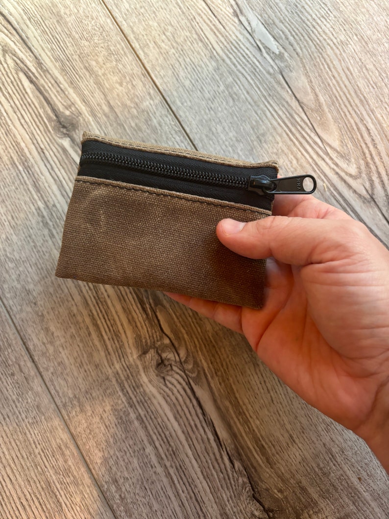 May include: A small brown canvas zipper pouch with a black zipper.