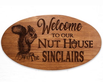 May include: Welcome to our Nut House, The Sinclairs. A wooden oval sign with a squirrel holding an acorn, engraved with the text.