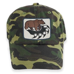 May include: A green camouflage baseball cap with a brown bear paw print patch. The patch features a brown bear walking on a paw print.