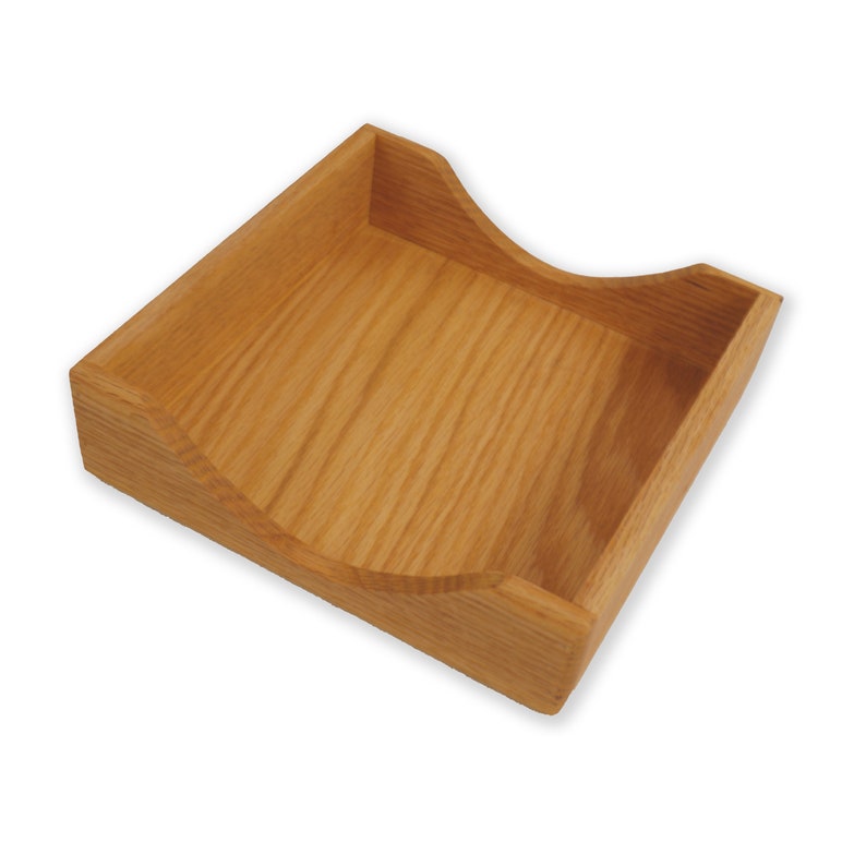 May include: A wooden napkin holder with a curved, open design. The holder is made of light brown wood with a natural grain pattern.