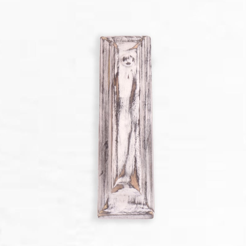 May include: A whitewashed wooden wall shelf with a distressed finish. The shelf has a rectangular shape with a raised edge around the perimeter.