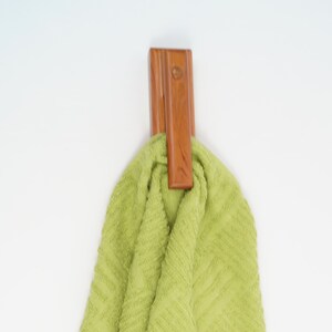 May include: A wooden towel hook with a green towel hanging from it.