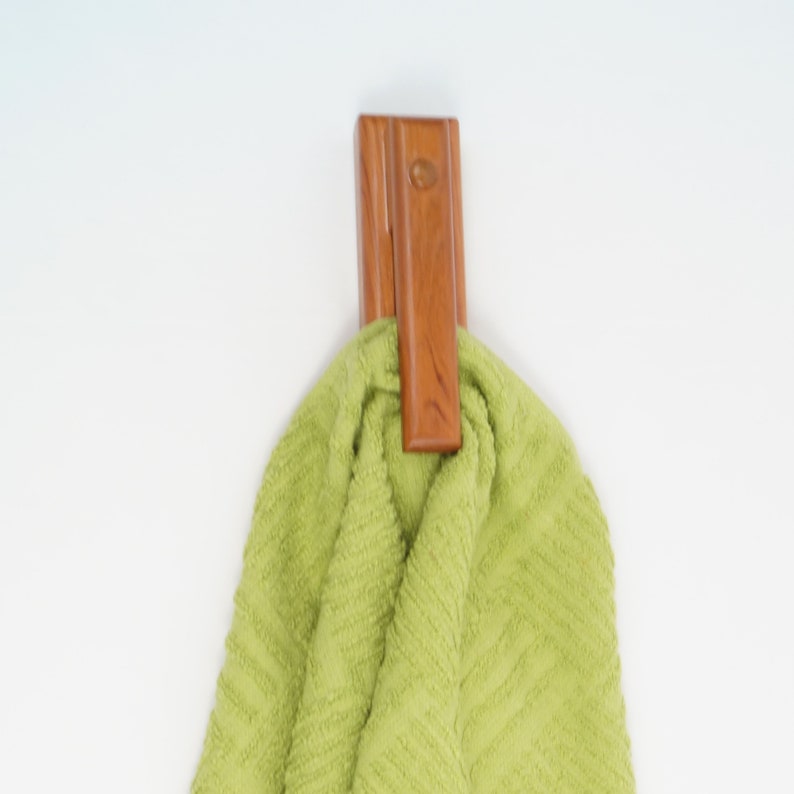 May include: A wooden towel hook with a green towel hanging from it.