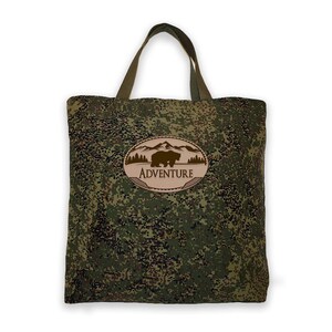 May include: A green camouflage tote bag with a brown oval patch that says "ADVENTURE" and features a silhouette of a bear in front of mountains.