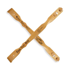 Puede incluir: Dos rascadores de espalda de madera con texto grabado. Un rascador de espalda tiene el texto "Merry Christmas!" y el otro tiene el texto "Your Text Here" y "Love, Your Names Here".