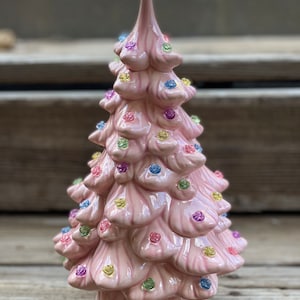 Könnte beinhalten: Ein rosa Keramikk Weihnachtsbaum mit bunten Lichtern. Der Baum ist mit kleinen, glitzernden Ornamenten geschmückt.