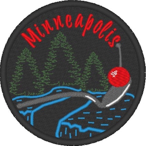 May include: Embroidered patch with a black background and the text "Minneapolis" in red. The patch features a stylized image of a river with a bridge, trees, and a red cherry.
