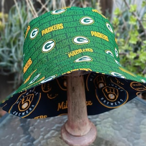 May include: Green and yellow reversible bucket hat with the words "Packers" and "Brewers" printed on it.