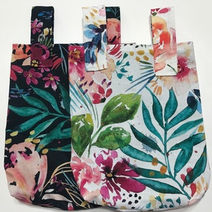 May include: Three fabric tote bags with floral patterns. The bags are black, white, and light blue with pink, green, and yellow flowers. The bags have a loop handle at the top.
