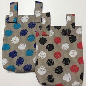 Peut inclure: Deux sacs fourre-tout en toile beige avec des motifs de couleurs différentes. Le sac à gauche a des motifs de gribouillis bleus, blancs et turquoise. Le sac à droite a des motifs de gribouillis rouges, noirs et blancs.