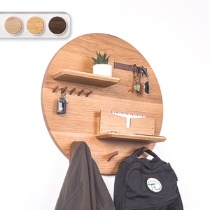 May include: A round wooden wall organizer with shelves, hooks, and a small plant. It has a brown finish and is perfect for organizing keys, mail, and other small items.
