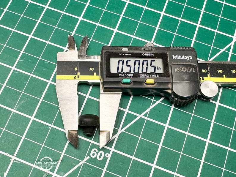 May include: A close-up of a digital caliper measuring a small black object. The caliper reads 0.5005 inches.
