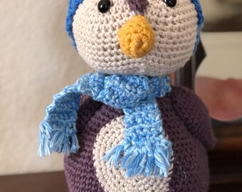 Adorable pingüino de amigurumi de ganchillo con gorro y bufanda.