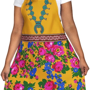 May include: Mustard yellow apron with a turquoise necklace design and a floral pattern of pink roses and blue flowers. The apron has a black neck strap and a brown patterned band across the middle.