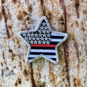 May include: A white star-shaped patch with a red stripe and black and white stripes, resembling the American flag.
