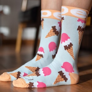 May include: A pair of blue socks with a pattern of ice cream cones. The socks have a light blue background with pink and brown ice cream cones.