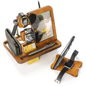 May include: Wooden organiser with compartments for a watch, phone, wallet, sunglasses, and a pen. It also has a small picture frame with a photo of a child.