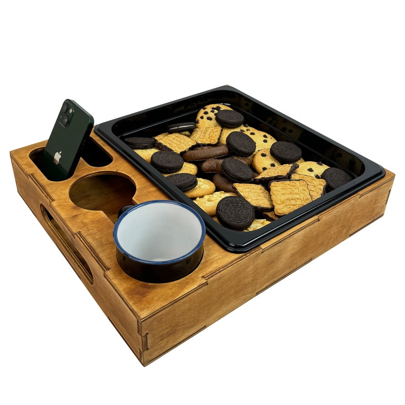May include: A wooden tray with a black tray insert, a cup, a phone, and a variety of cookies. The tray is perfect for serving snacks and drinks.