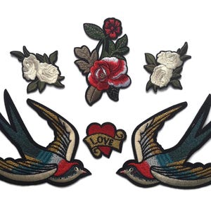May include: Two embroidered iron-on patches featuring a pair of flying swallows with red, blue, and gold accents. The patches also include a red heart with the word "LOVE" on it and three white roses with green leaves.