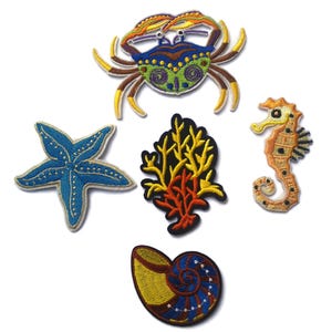 Puede incluir: Conjunto de cinco parches bordados de colores para planchar que representan un cangrejo, una estrella de mar, un caballito de mar, un coral y una concha.
