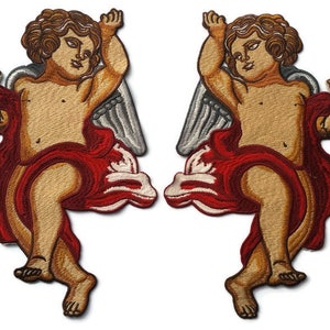 May include: Two embroidered patches of cherubs with wings, each wearing a red and white robe. The cherubs have brown hair and are depicted with a playful expression.