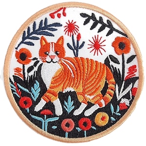Può includere: Toppa ricamata con un gatto tabby arancione e bianco, circondato da fiori e foglie colorate. La toppa ha un bordo beige e uno sfondo bianco. Il design include elementi rossi, arancioni, blu e neri.