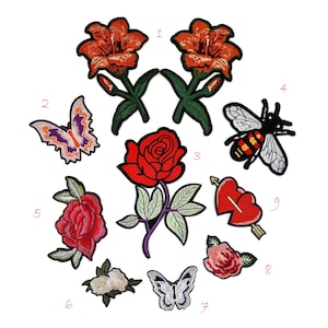 May include: A collection of embroidered patches featuring floral and insect designs. Includes red roses, orange lilies, a butterfly with purple and orange wings, and a bee with black and yellow stripes. Also includes a heart pierced by an arrow.