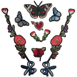 May include: A set of embroidered iron-on patches featuring floral designs, butterflies, and a heart. The patches are in shades of red, blue, green, and black.
