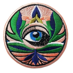 May include: A round embroidered patch with a large blue eye surrounded by green, blue, and white floral designs on a peach background.