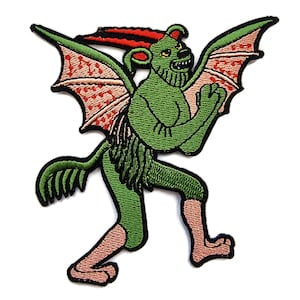 May include: Green and red embroidered patch of a winged, horned, and fanged creature with a human-like body and a lion-like head.