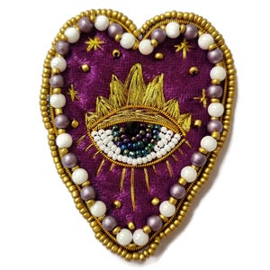 Parche de corazón con ojo místico, bordado a mano en terciopelo dorado y morado.