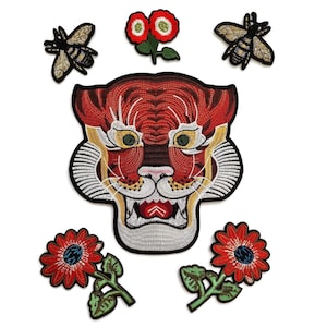 May include: Embroidered patches featuring a tiger face, bees, and flowers. The tiger patch is red, white, and yellow with intricate stitching. The bees are gold and black, and the flowers are red with green leaves. These patches are ideal for adding flair to clothing or accessories.