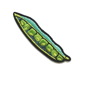 Könnte beinhalten: Gestickter Aufnäher einer grünen Erbsenschote mit sechs Erbsen. Der Aufnäher hat einen schwarzen Rand und weist Grün- und Blautöne auf. Das Design ist detailliert mit sichtbaren Nähten, wodurch ein strukturiertes Aussehen entsteht.