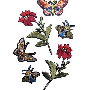 Snyggt precisionsbroderat strykmärke med blomma, fjäril och guldfärgad insekt på jacka