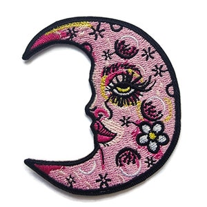 May include: Pink embroidered crescent moon patch featuring a stylised face, eyelashes, and a flower. The moon is decorated with stars and swirls.