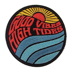 Könnte beinhalten: Ein runder, schwarzer gestickter Aufnäher mit einem roten, gelben und blauen Design. Der Aufnäher zeigt einen Sonnenuntergang mit einer Sonne und Strahlen, Wellen und dem Text "Good Vibes High Tides".