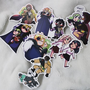 May include: A selection of colourful stickers with cartoon illustrations of couples in different poses. Some stickers depict characters embracing, while one has the text "Marry Me!". The stickers are on a white, textured surface.