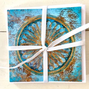 May include: A set of greeting cards featuring a blue and gold mandala design. The cards are tied together with a white ribbon.