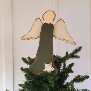 Op de afbeelding: Een houten engel voor op de boomtop met een groene body, crèmekleurige vleugels met bruine randen en een crèmekleurige ster. De engel staat bovenop een groene kerstboom.