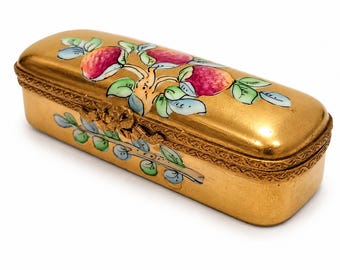 May include: A rectangular gold-toned metal box with a hinged lid. The surface features a hand-painted design of red fruits and green leaves on the top and front. The edges of the lid and base are decorated with a textured, repeating pattern.