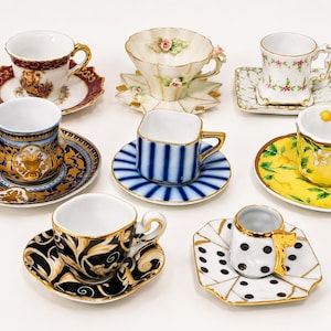 Pode incluir: Uma coleção de oito chávenas de café expresso com pires em cerâmica, apresentando designs variados, incluindo padrões florais, riscas azuis e brancas, limões amarelos, bolinhas pretas e brancas e decorações barrocas com detalhes dourados.
