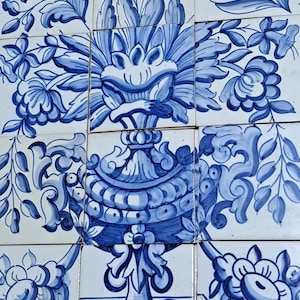 Könnte beinhalten: Ein Satz von neun blauen und weißen Keramikfliesen, die ein Blumenarrangement in einer Vase darstellen. Die Vase ist verziert und hat ein detailliertes Design. Die Blumen sind stilisiert und haben einen verspielten Charakter.