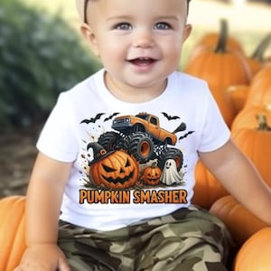 May include: A smiling baby wearing a white t-shirt with a Halloween graphic and the text "PUMPKIN SMASHER". The baby is sitting in a wheelbarrow filled with orange pumpkins, wearing camouflage pants, a brown cap, and white sneakers.
