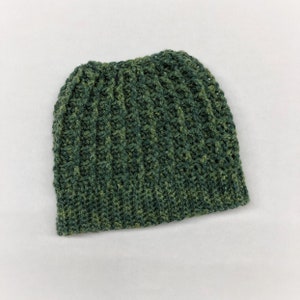 May include: A green and brown crocheted beanie hat. The hat is made with a textured stitch and has a slouchy fit.