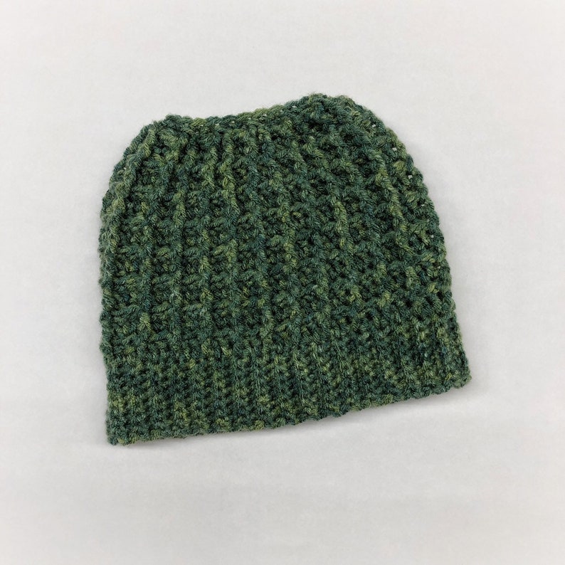 May include: A green and brown crocheted beanie hat. The hat is made with a textured stitch and has a slouchy fit.